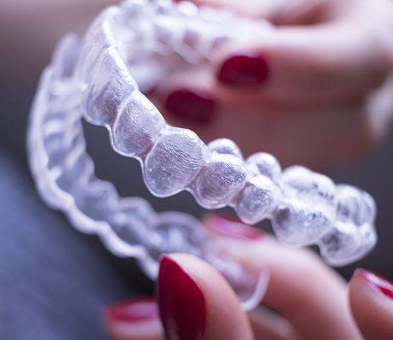 Hand holding Invisalign clear braces tray