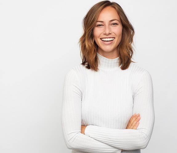 Woman in white sweater smiling in front of white background