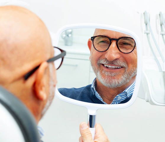 Patient with black glasses smiling at reflection