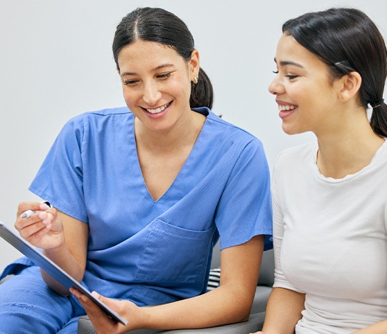 Dental assistant showing patient forms on clipboard