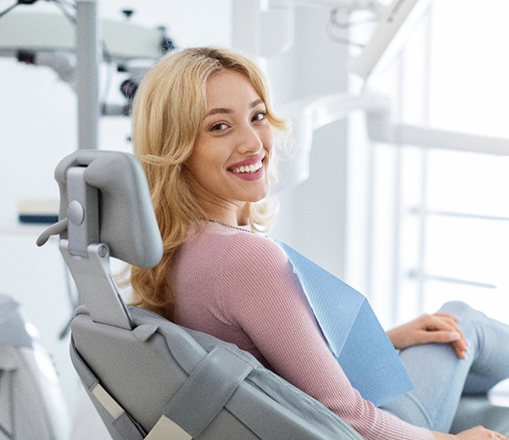 Blonde woman in dental chair looking back and smiling