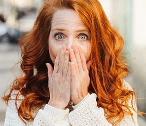 Woman with knocked out tooth covering her mouth