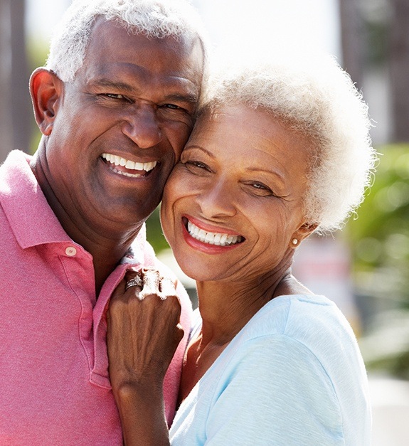 Man and woman with healthy smiles after tooth replacement with dental implants