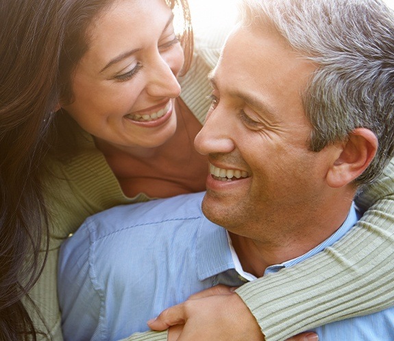 Man and woman with healthy smiles enjoy the benefits of dental implants