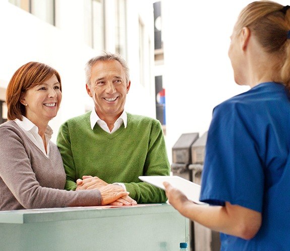 Older couple checking in at dental office reception desk