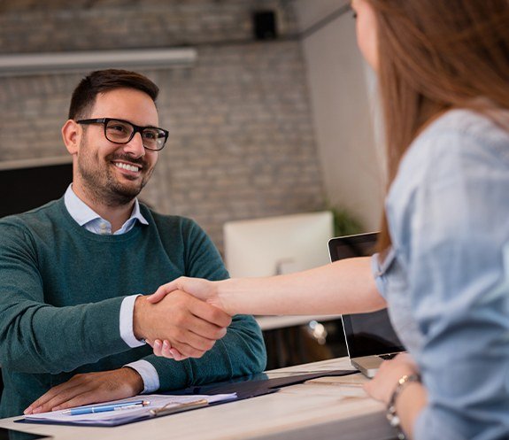 Dental patient shaking hands with dental team member