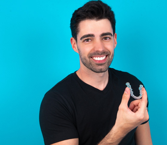 Man in black t-shirt holding Invisalign smiling