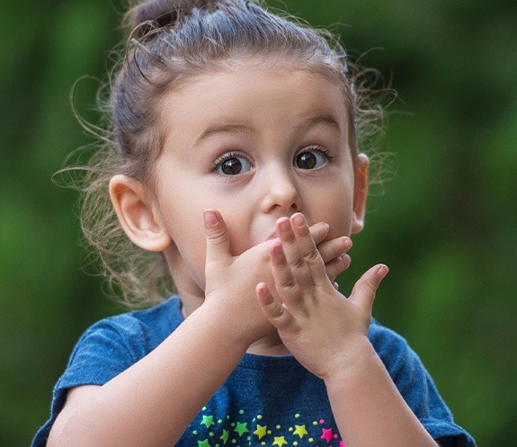 Child covering mouth before emergency dentistry