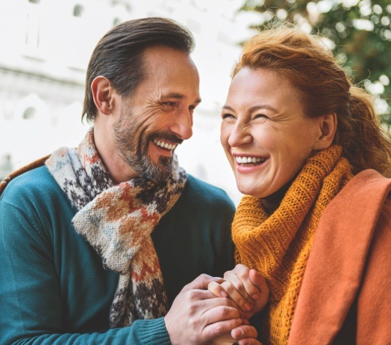 Man and woman with healthy smiles after replacing missing teeth