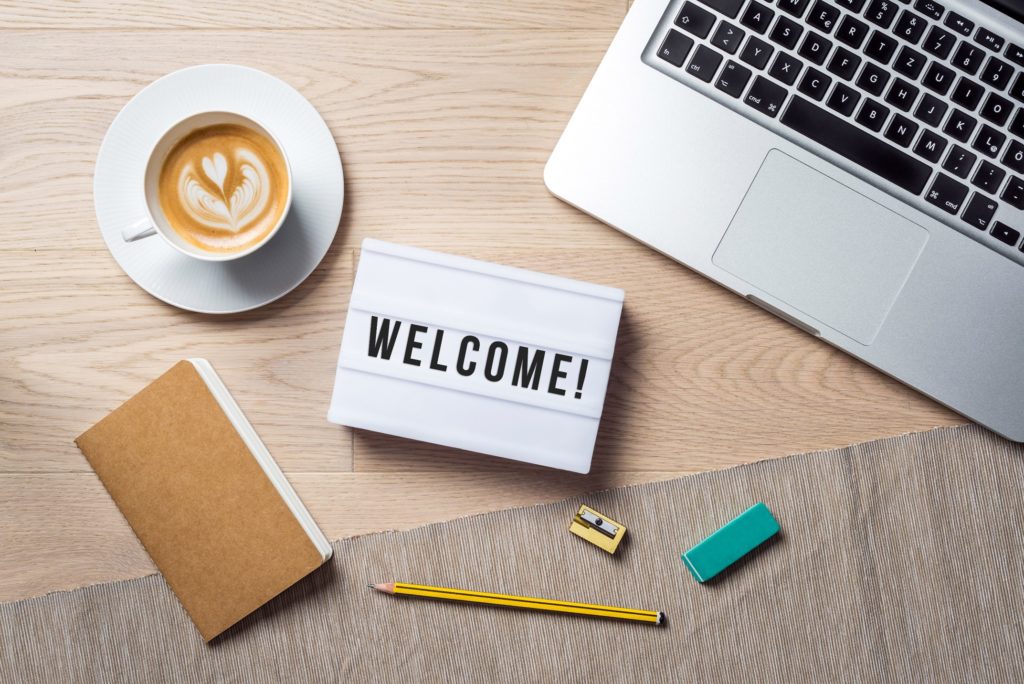 Welcome sign lying on desk with coffee and laptop