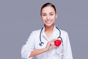 a dentist smiling and holding a small heart 