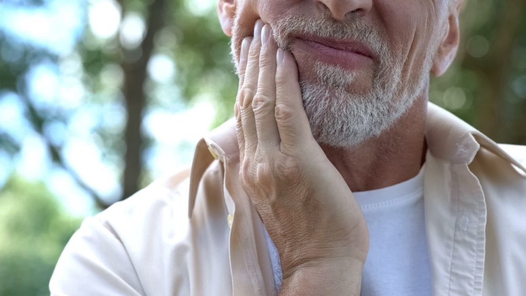 person experiencing dental emergency holding cheek