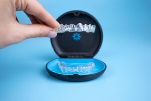 Hand holding Invisalign clear aligner.